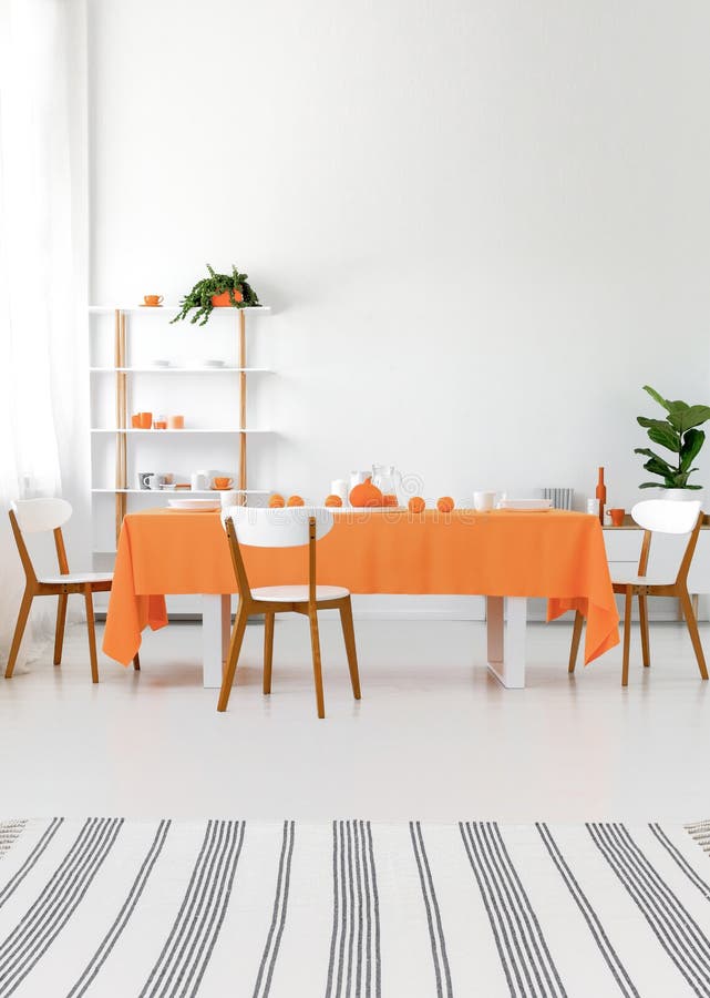 Interior moderno Tabla larga del comedor con las sillas Paredes y piso blancos, detalles anaranjados Concepto real de la foto imagen de archivo libre de regalías Interior moderno Tabla larga del comedor con las sillas Paredes y piso blancos, detalles anaranjados Concepto real de la foto imagen de archivo libre de regalías
