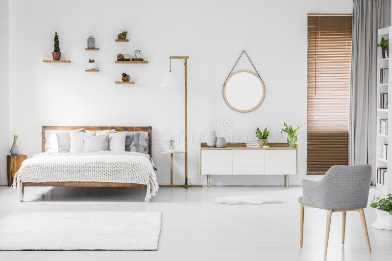 Interior spațios al unui dormitor alb, cu pat din lemn stock images