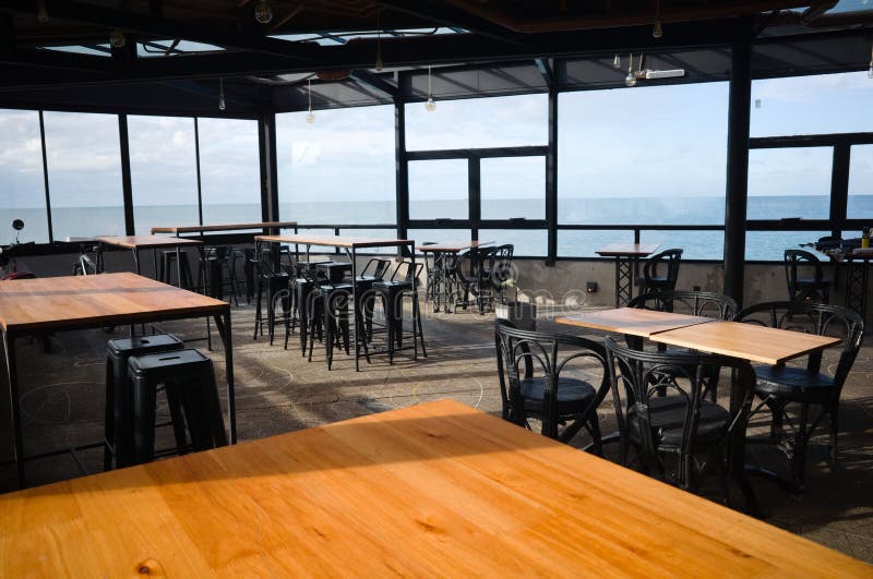 Interior view of closed empty cafe. Chairs and tables of empty restaurant on the beach with ocean view during quarantine in 2020. Mar del Plata, Argentina. Interior view of closed empty cafe. Chairs and tables of empty restaurant on the beach with ocean view during quarantine in 2020. Mar del Plata, Argentina