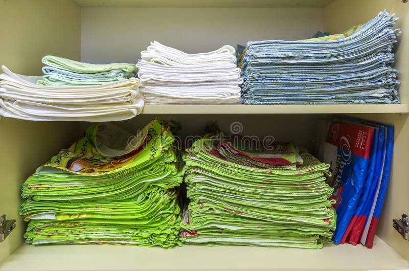 Interior of white plastic cabinet or clothing wardrobe with open doors with stacked pile of clean colorful linen. Household and royalty free stock photo Interior of white plastic cabinet or clothing wardrobe with open doors with stacked pile of clean colorful linen. Household and royalty free stock photo