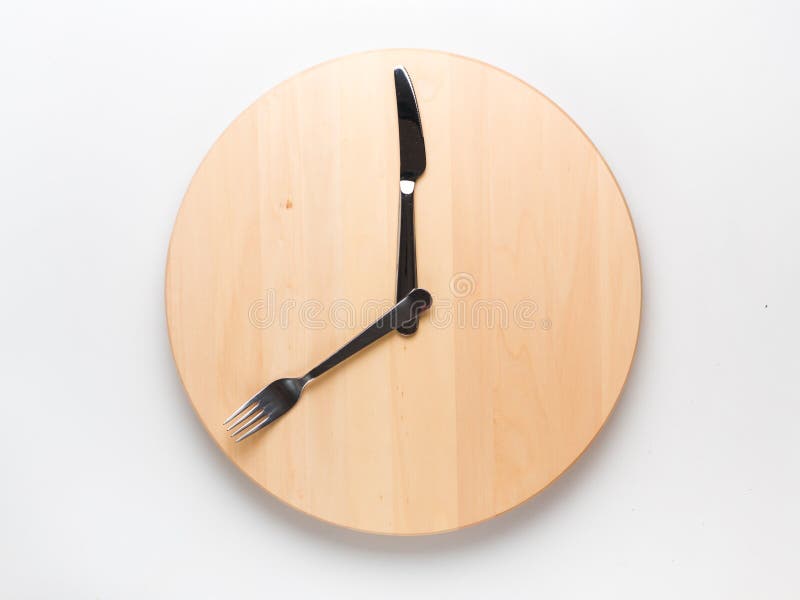 Intermittent fasting and skip breakfast concept - empty wooden round tray or trencher with cutlery as clock hands on white background. Eight hour feeding window concept or breakfast time concept. Intermittent fasting and skip breakfast concept - empty wooden round tray or trencher with cutlery as clock hands on white background. Eight hour feeding window concept or breakfast time concept