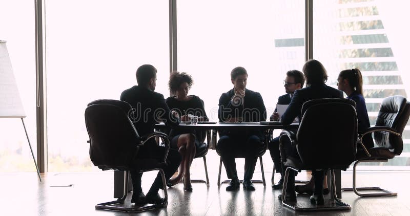 Internationale zakenmensen die aan de tafel van de bestuurskamer zitten te onderhandelen