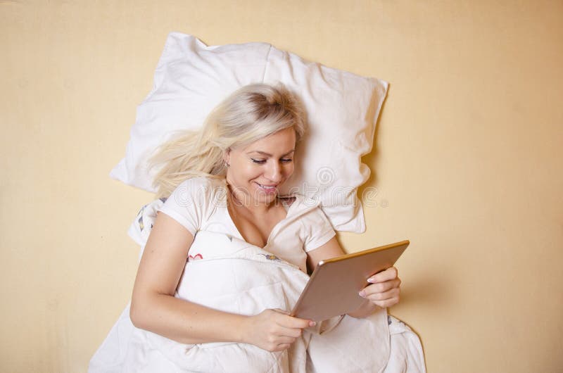 Internet de la ojeada en la cama, mujer joven hermosa foto de archivo libre de regalías Internet de la ojeada en la cama, mujer joven hermosa foto de archivo libre de regalías
