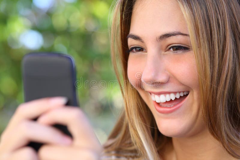 Internet feliz da consultação da mulher em seu telefone esperto exterior foto de stock Internet feliz da consultação da mulher em seu telefone esperto exterior foto de stock