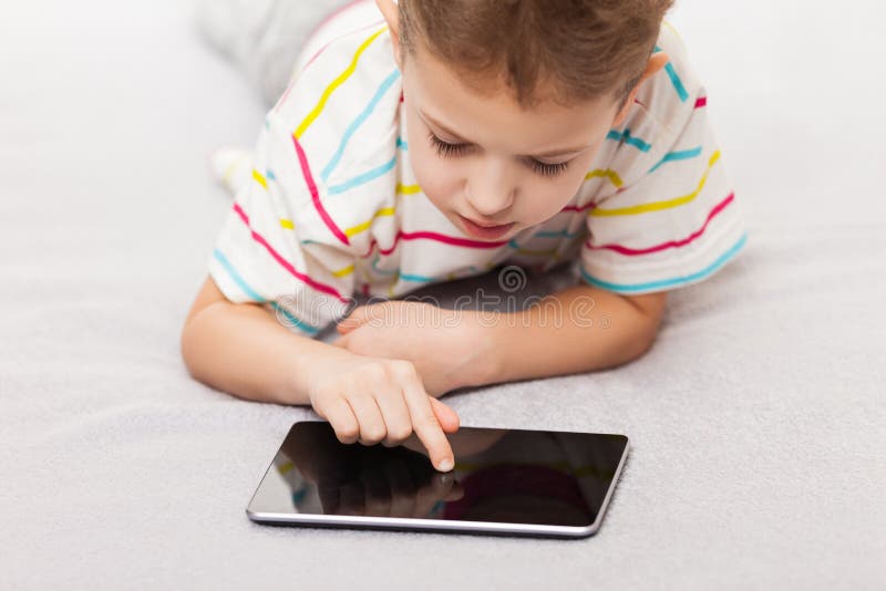 Internet giocante o praticante il surfing del ragazzo sorridente del bambino sulla compressa co fotografie stock libere da diritti Internet giocante o praticante il surfing del ragazzo sorridente del bambino sulla compressa co fotografie stock libere da diritti