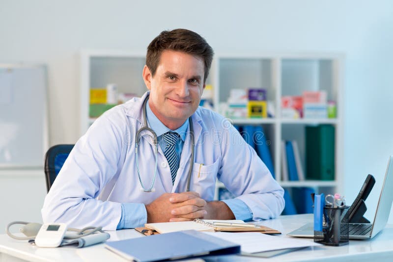 Portrait of general practitioner sitting at the table in his office. Portrait of general practitioner sitting at the table in his office