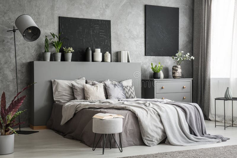 Interno alla moda della camera da letto nel grey con un grande letto con le lenzuola fotografia stock