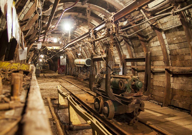 Interno del passaggio della miniera in sotterraneo con le rotaie, la luce ed il trasporto