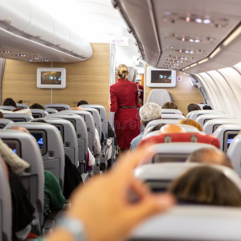 Interno dell'aeroplano commerciale con l'hostess che cammina la navata laterale immagini stock libere da diritti Interno dell'aeroplano commerciale con l'hostess che cammina la navata laterale immagini stock libere da diritti