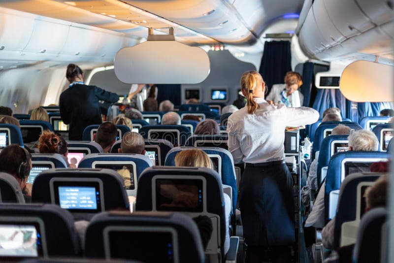 Interno di grande aeroplano commerciale con le hostess che serviscono i passeggeri sui sedili durante il volo