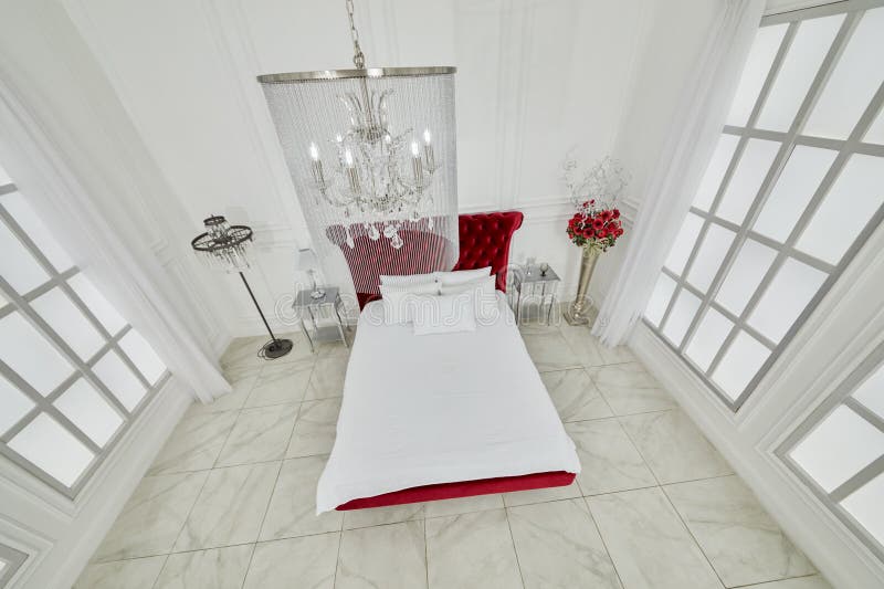 Interno di spaziosa camera da letto bianca con grande rosso fotografia stock libera da diritti