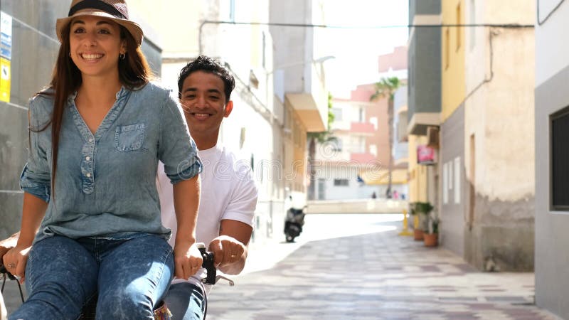 Interracial couple have fun together riding a bike in outdoor in the city - happiness and joy young people interracial boyfriend