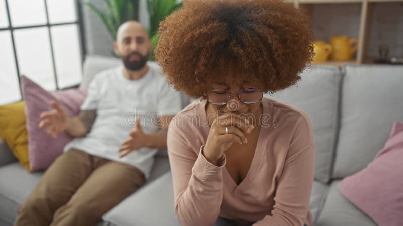 Interracial couple having a serious discussion on a cozy sofa indoors royalty free stock image
