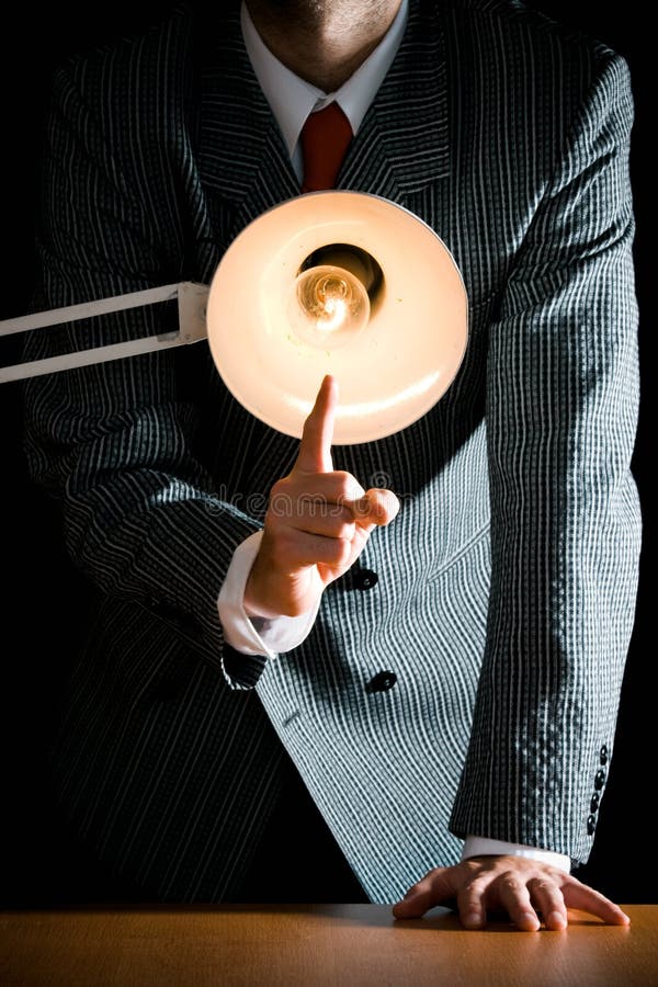 Suggestive interrogation concept - interrogating person standing behind desk lamp