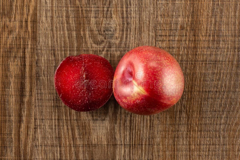 Interspecific plommoner för ny pluot på brunt trä royaltyfri fotografi Interspecific plommoner för ny pluot på brunt trä royaltyfri fotografi