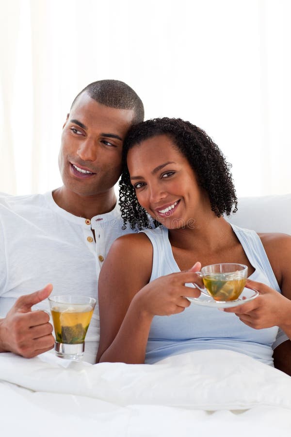 Intimate couple drinking a cup of tea on their bed. Concept of love.