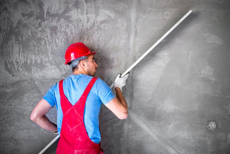 Intonacatore sul lavoro sul cantiere, livellante le pareti e controllante qualità Lavoratore dell'industria sul cantiere fotografie stock libere da diritti Intonacatore sul lavoro sul cantiere, livellante le pareti e controllante qualità Lavoratore dell'industria sul cantiere fotografie stock libere da diritti