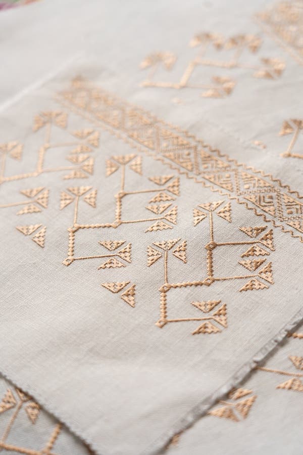 Intricate embroidery featuring geometric patterns on light fabric stock images