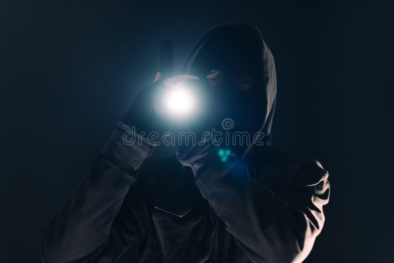 Armed burglar intruder with flashlight torch at night, low key selective focus. Armed burglar intruder with flashlight torch at night, low key selective focus