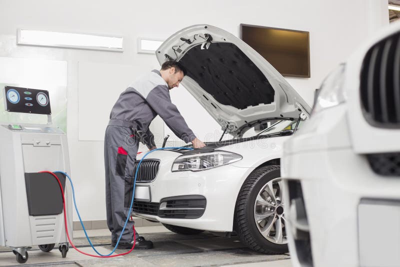 Full length of male engineer examining car in automobile repair shop. Full length of male engineer examining car in automobile repair shop