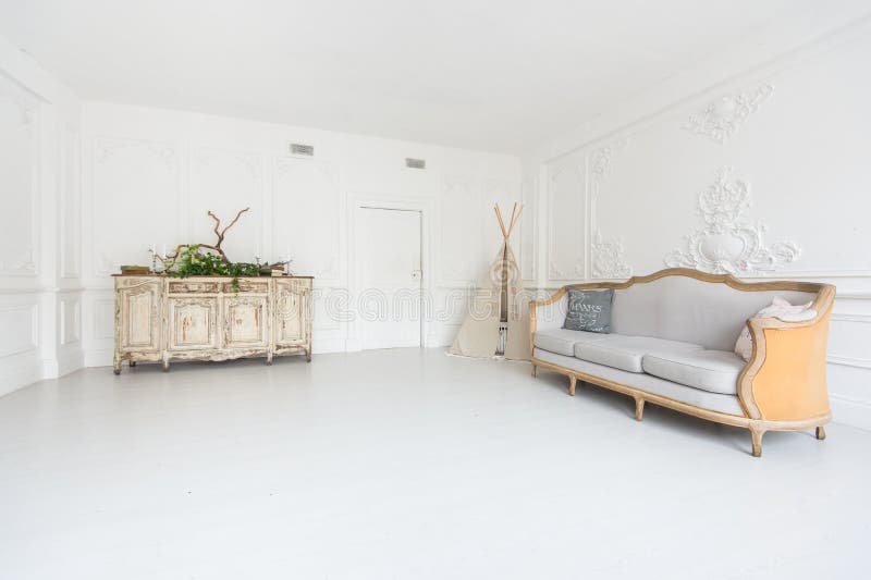 Intérieur léger luxueux de la salle avec le stuc sur les murs, le sofa, le tipi et le coffre des tiroirs décorés des usines photos stock Intérieur léger luxueux de la salle avec le stuc sur les murs, le sofa, le tipi et le coffre des tiroirs décorés des usines photos stock
