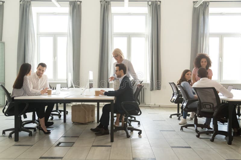 Big modern office room interior with busy business team people working on computers talking in coworking enterprise open space, multi-ethnic staff employees sitting at desks at corporate workplace. Big modern office room interior with busy business team people working on computers talking in coworking enterprise open space, multi-ethnic staff employees sitting at desks at corporate workplace