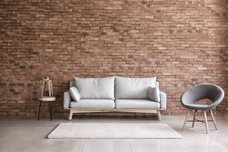 Intérieur moderne de salon avec le sofa et le fauteuil confortables près du mur de briques images stock