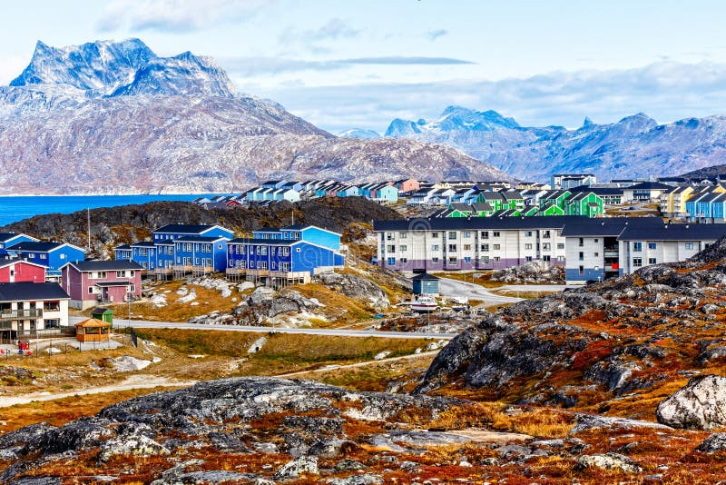 Inuit houses and cottages scattered across tundra landscape in residential suburb of Nuuk city with fjord and mountains in the