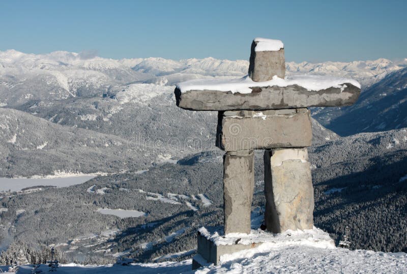 An Inukshuk (symbol of the 2010 winter olympic games and a traditional native sculpture) stands on Whistler mountain overlooking Blackcomb mountain.