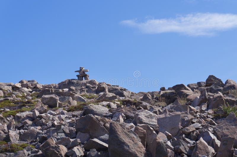 Inukshuk röse överst av stenkullen mot blå himmel royaltyfria bilder Inukshuk röse överst av stenkullen mot blå himmel royaltyfria bilder