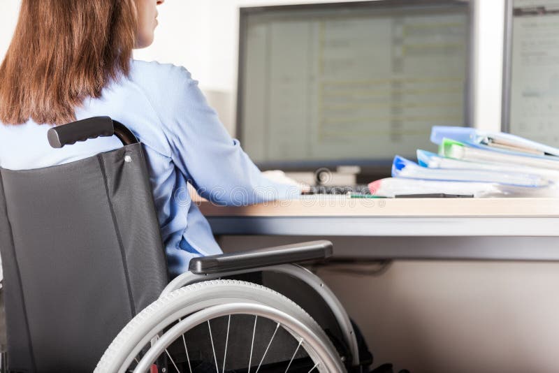 Invalid or disabled woman sitting wheelchair working office desk computer