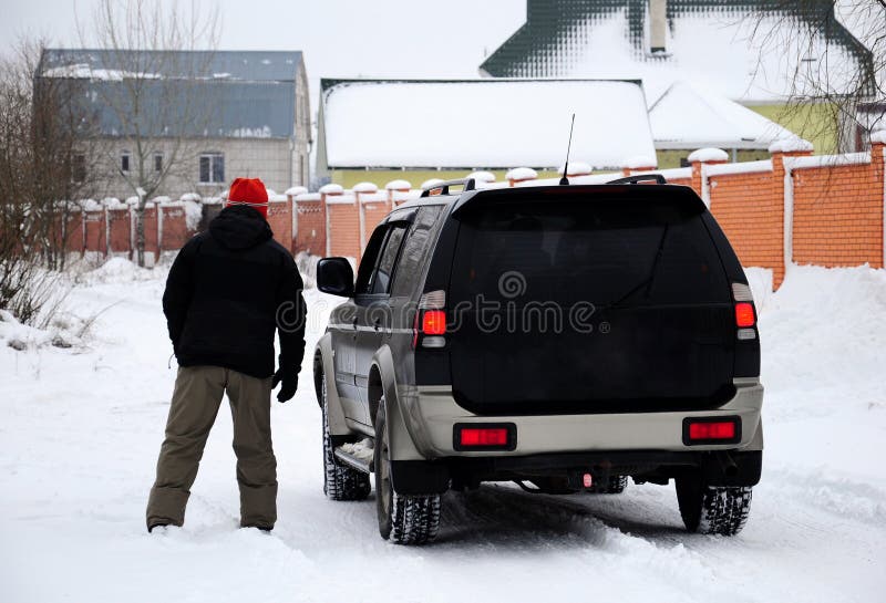 A man standing in front of a jeep in winter. A man standing in front of a jeep in winter