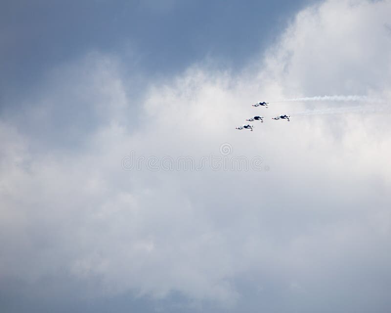 Four USAF Thunderbirds fly inverted against a cloudy sky, trailing smoke. Four USAF Thunderbirds fly inverted against a cloudy sky, trailing smoke.