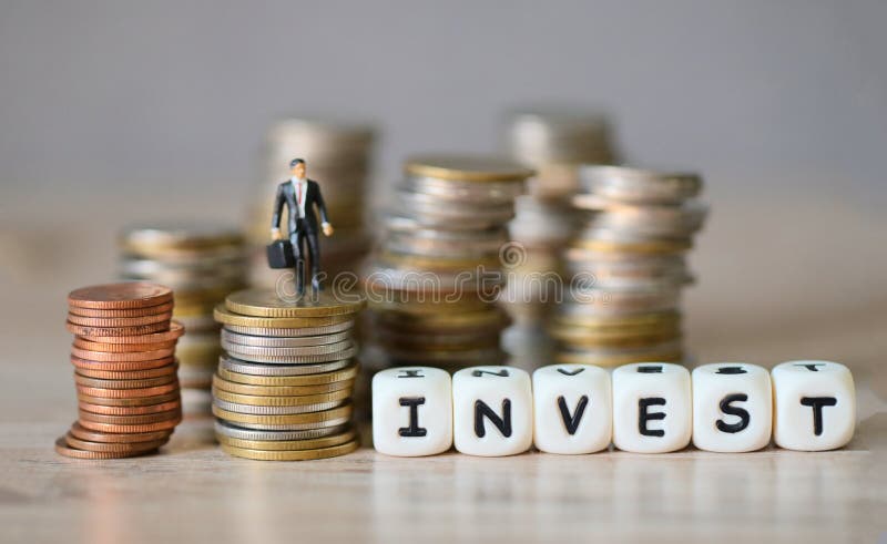 Invest message and business man standing on a coin on wooden table background, invest business economy concept of money and stock photos