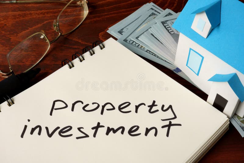 Property Investment written on notebook with model of house and dollars. Property Investment written on notebook with model of house and dollars.