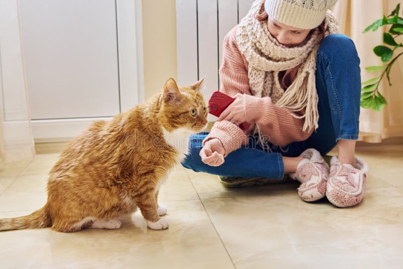 Invierno frío temporada de otoño niña calentándose cerca del radiador de calefacción con gato imagen de archivo