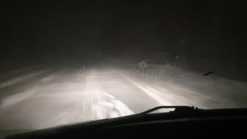 Invierno noche coche de carretera en una vista de ventisca a través de la ventana del conductor