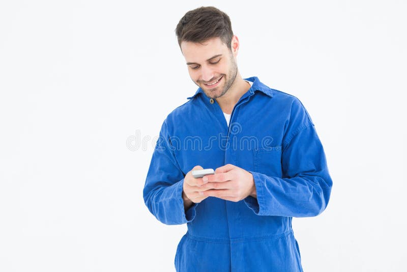 Invio di messaggi di testo maschio del meccanico tramite il telefono cellulare immagini stock libere da diritti Invio di messaggi di testo maschio del meccanico tramite il telefono cellulare immagini stock libere da diritti