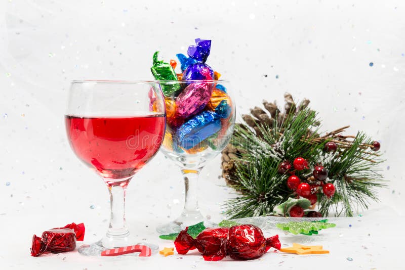 Christmas party treats of wine and wrapped chocolate candy sweets. Treats to enjoy the merry holiday season.on a snowy white background. Christmas party treats of wine and wrapped chocolate candy sweets. Treats to enjoy the merry holiday season.on a snowy white background.