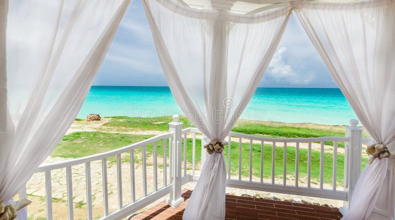 inviting pretty view through the fluffy open curtains of a beach gazebo during the preparation for a wedding ceremony