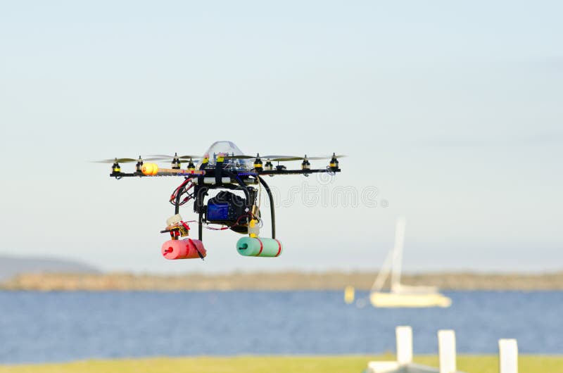 Remote-controlled surveillance helicopter with eight rotors flying over water near yacht carrying camera. Remote-controlled surveillance helicopter with eight rotors flying over water near yacht carrying camera
