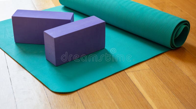 Yoga mat and exercise bricks on wooden floor. Pilates, yoga class, training at home and healthy lifestuyle concept. Yoga mat and exercise bricks on wooden floor. Pilates, yoga class, training at home and healthy lifestuyle concept