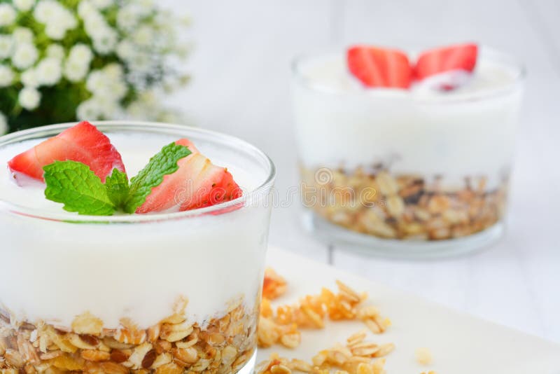 Iogurtes de vidro com cereais e morangos, café da manhã fotografia de stock Iogurtes de vidro com cereais e morangos, café da manhã fotografia de stock