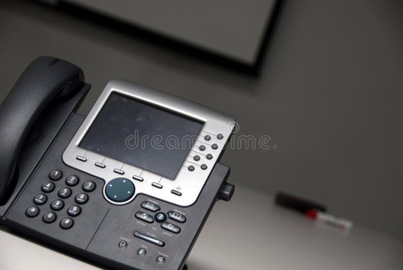 IP phone in the foreground of conference room and dry erase marker in background. IP phone in the foreground of conference room and dry erase marker in background