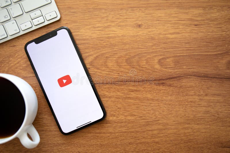 Dùng iPhone X để khám phá YouTube Google với tính năng chơi video nền tràn đầy tiện ích trên bàn làm việc gỗ đẹp mắt.