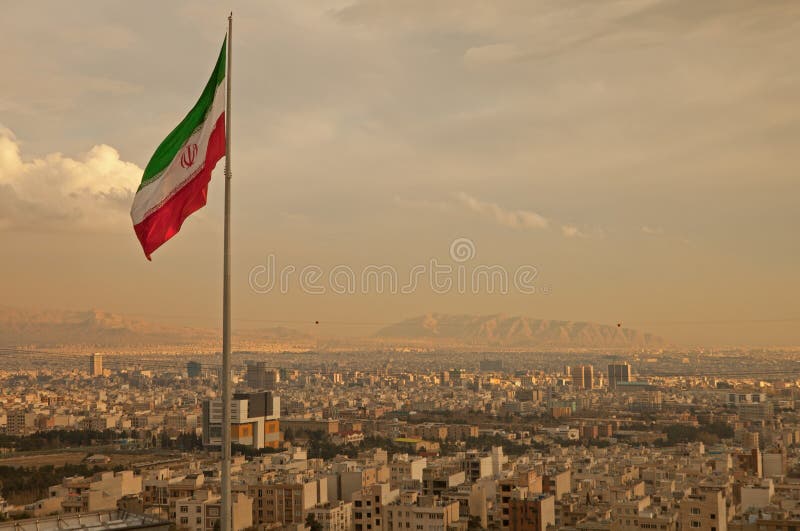 Írán vlajka mávání ve větru nad panorama města Teheránu rozsvítí oranžová záře slunce.