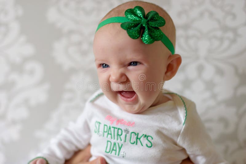 Irish baby with big blue eyes laughing and wearing St Patricks Day outfit and shamrock headband. Irish baby with big blue eyes laughing and wearing St Patricks Day outfit and shamrock headband