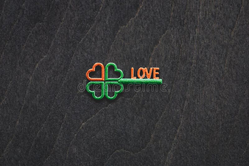 Irish green shamrock shape key with orange heart, four-leaf clover good luck charm, on wooden background