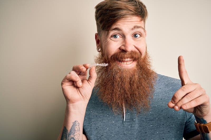 Irish Rothaarigemann mit dem Bart, der zahnmedizinischem unsichtbaren Ausrichtungstransport für Zahnkorrektur überrascht mit einem lizenzfreie stockfotos