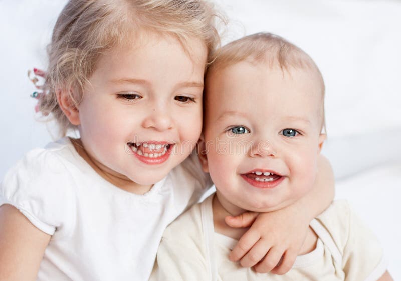 Happy little sister hugging her brother on a white background. Happy little sister hugging her brother on a white background